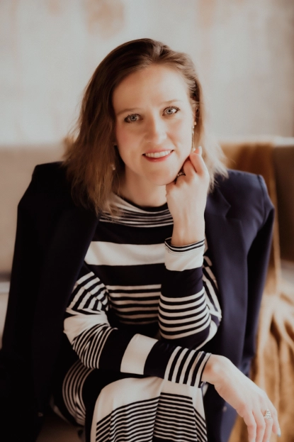 Headshot of Rachel wearing a long-sleeve shirt with black and white stripes wth a black jacket over her shoulders.