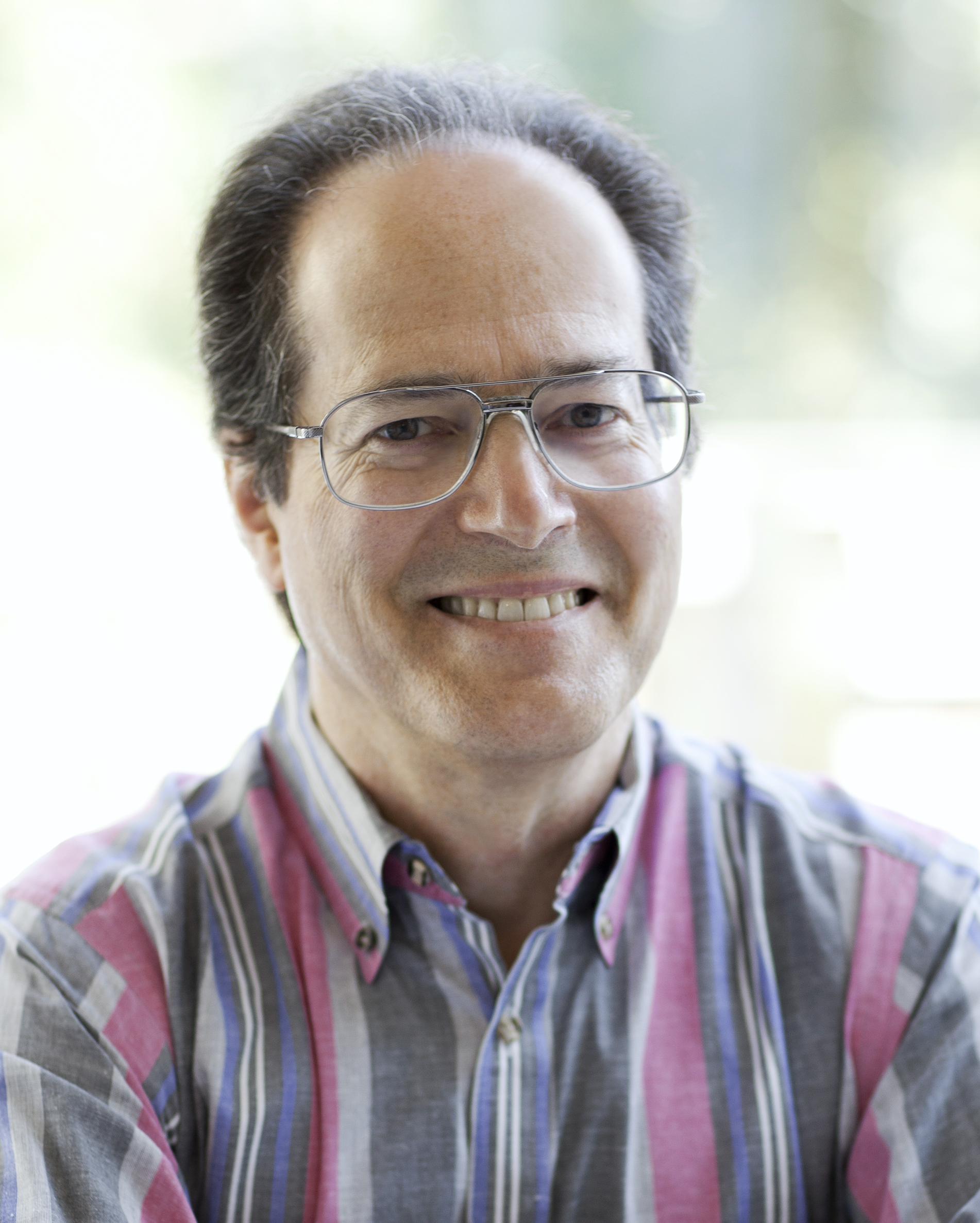 Headshot of Castleman wearing glasses and a striped button-up shirt.