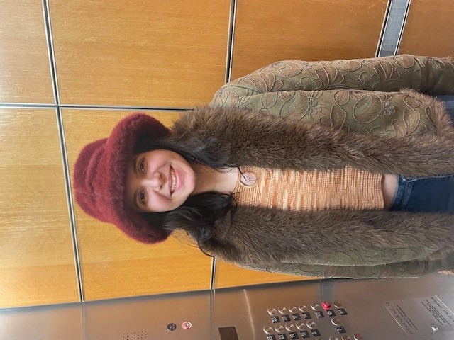 Sciabbarrasi in an elevator wearing a fur-lined jacke and red bucket hat.
