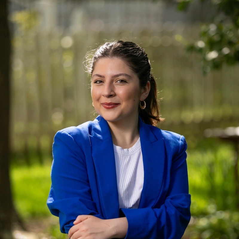 Gwen wearing a white shirt and navy blazer on top with arms crossed in front.