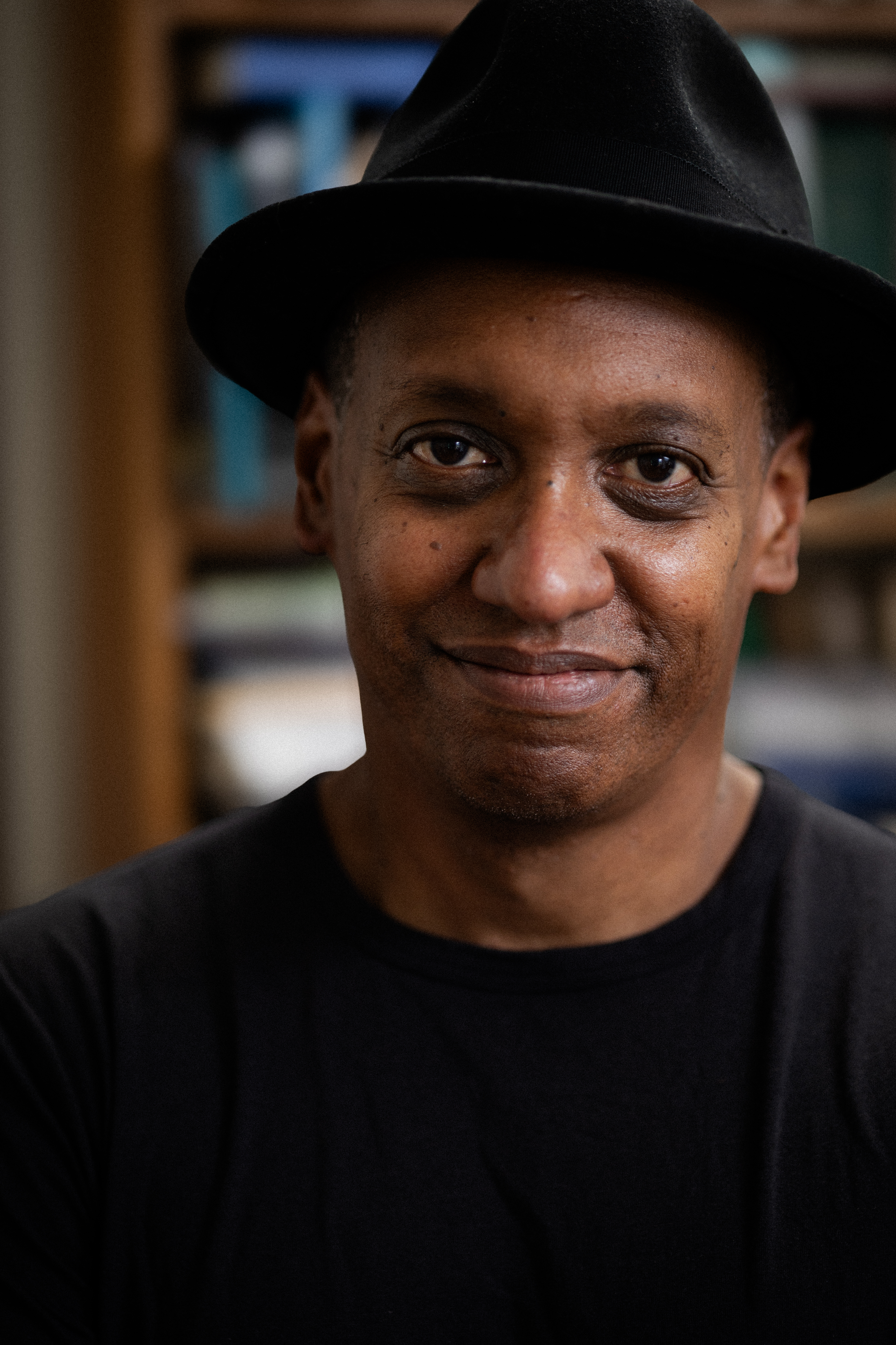 Headshot of Thompson wearing a black shirt and fedora.
